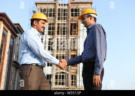 Two engineers shaking hands at a construction site Stock Photo