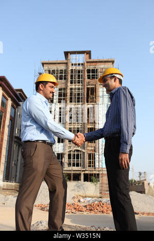 Two engineers shaking hands at a construction site Stock Photo