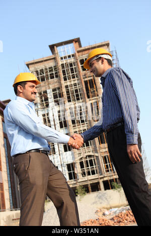 Two engineers shaking hands at a construction site Stock Photo