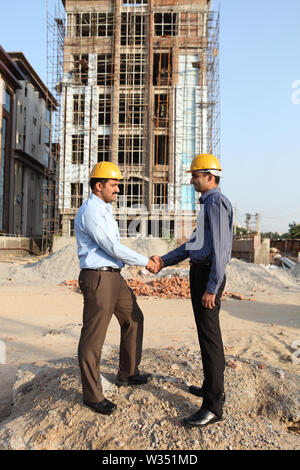 Two engineers shaking hands at a construction site Stock Photo
