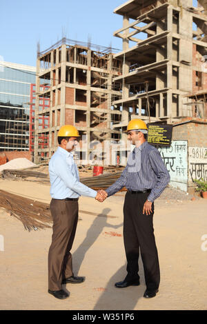 Two engineers shaking hands at a construction site Stock Photo
