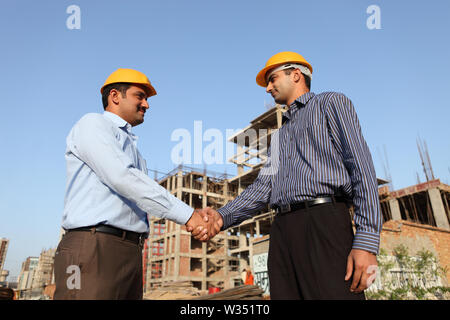 Two engineers shaking hands at a construction site Stock Photo