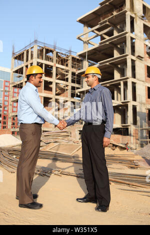 Two engineers shaking hands at a construction site Stock Photo