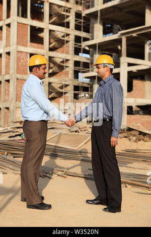 Two engineers shaking hands at a construction site Stock Photo