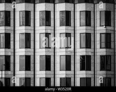 A black and white, abstract image of angular windows on the front of a modern building Stock Photo