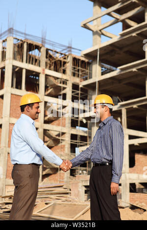 Two engineers shaking hands at a construction site Stock Photo