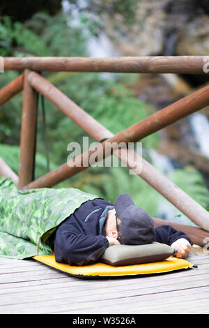 Fun Camping, Happy Man Sleeping in a Sleeping bag in the Mountain Stock Photo