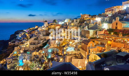 Tourists in luxury restaurants and on Oia Castle wait for the sunset with Caldera View and the famous Windmill in Oia, Santorini , Greece at 04 June 2 Stock Photo