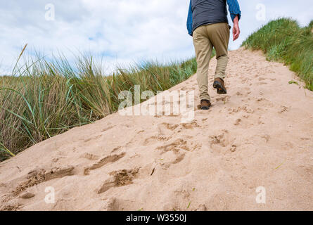 Senior man trudging up steep sand dune slope, Aberlady Nature Reserve, East Lothian, Scotland, UK Stock Photo