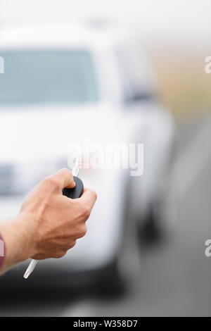 Car key - man locking pressing car keys on new car or rental car. Close up of hand with electronic key. Stock Photo