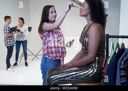 Make Up Artist Working On Fashion Shoot In Photographers Studio Stock Photo