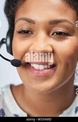 Close Up Of Businesswoman Wearing Telephone Headset In Customer Services Department Stock Photo