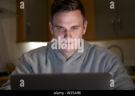 Suspicious Looking Man Using Laptop In Evening At Home Stock Photo
