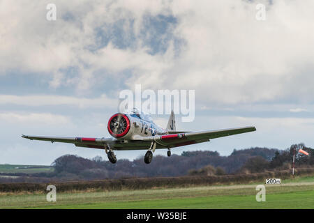 Harvard T6 Warbird approaching a grass airstrip with the landing gear coming down Stock Photo