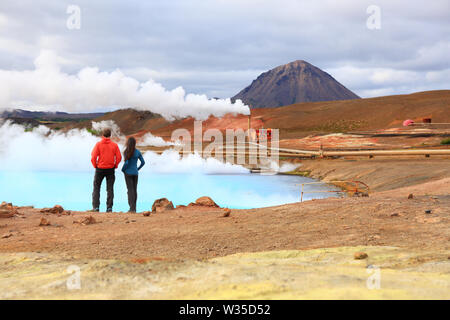 Iceland travel people by geothermal energy power plant and hot spring in Namafjall in Lake Myvatn area. Couple on travel in Icelandic nature landscape, Route 1 Ring Road. Stock Photo