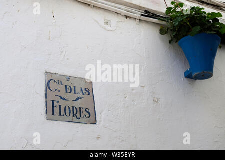 Calle de las Flores tiled sign on a wall in Cordoba, Andalusia, Spain; street of flowers of flower street, with a blue pot and plant. Stock Photo