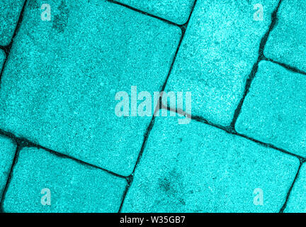 Detailed close-up of street pavement background with diagonal geometric pattern made of various square blocks. Textured rough surface toned in electri Stock Photo