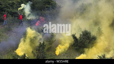 Hardheim, Germany. 12th July, 2019. Soccer: Test matches, FC Schweinberg - Borussia Dortmund. Before the match outside the stadium, football fans light Bengali fires in red and yellow. Credit: Karl-Josef Hildenbrand/dpa/Alamy Live News Stock Photo