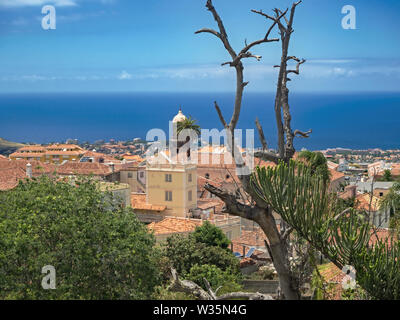 View over the red tiled roofs of the old town of La Orotava in the north of the Canary Island of Tenerife. In front of it the dark blue, calm Atlantic Stock Photo