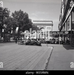 1960s, historical, daytime and people sitting outside La Maison du Cafe, a cafe-restaurant located on a sidewalk at the top end of the Champs-Elysees, within view of the famous parisan monument, the Arc de Triomphe. Stock Photo