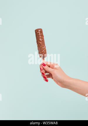 Woman holding delicious chocolate covered ice cream on stick against ...