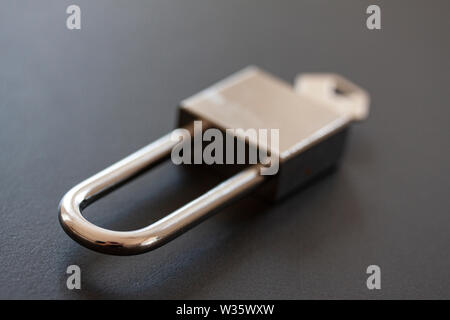 Stainless steel padlock with key on black background - Image Stock Photo