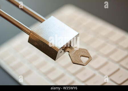 Stainless padlock with key in front of computer keyboard. PC network security, data security and antivirus protection concept. - Image Stock Photo