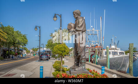 Tarpon Springs, Florida. A small historical waterside town with a sponge diver statue on the docks next to boats. Stock Photo