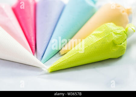 Piping bags with pastel color royal icing to decorate Easter sugar cookies. Stock Photo