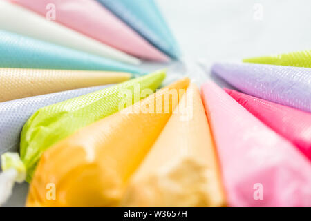 Piping bags with pastel color royal icing to decorate Easter sugar cookies. Stock Photo