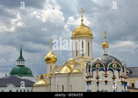 = Monastery Domes and Towers Against the Grey Clouds =  The shining beautiful cupolas, towers and roofs of Holy Trinity-St. Sergius Lavra in Sergiyev Stock Photo