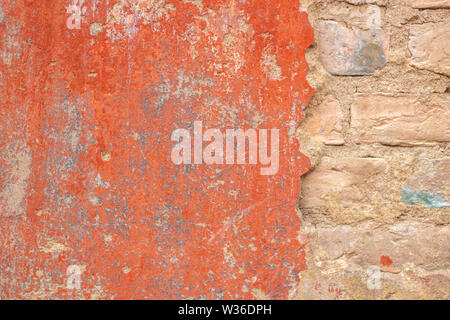 Old cracked weathered shabby red painted plastered peeled brick wall background Stock Photo