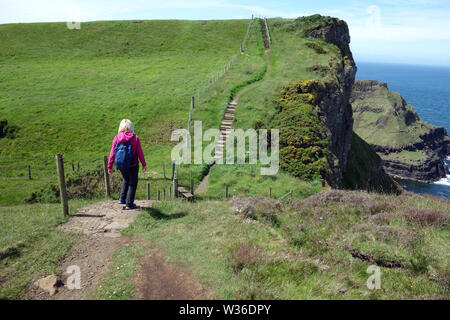 Woman Walking Towards Steps on the Giant's Causeway Coastal Path, County Antrim, Northern Ireland, UK Stock Photo