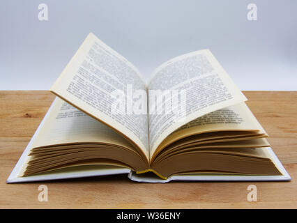 Open book on wooden table, white background Stock Photo