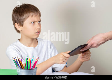 Video games addiction. Mother taking tablet away from the kid hands Stock Photo