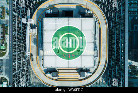 Aerial top view of helipad on the roof of a skyscraper iin downtown with cityscape view on sunny day Stock Photo