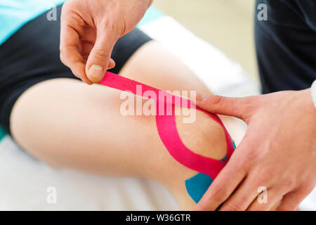 Kinesiotaping. Physical therapist applying tape to patient knee Stock Photo