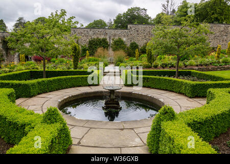 Well clipped box hedges surrounding a small pool with fountain at Bodnant Gardens, Conwy, Wales, UK Stock Photo