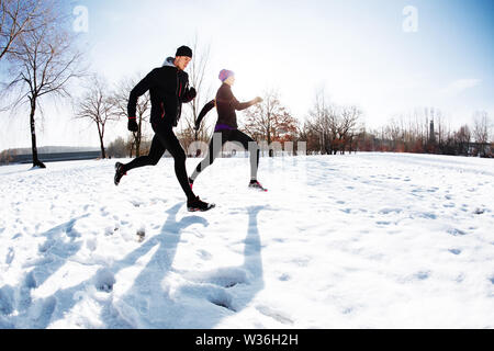 Couple running at park on snow Stock Photo