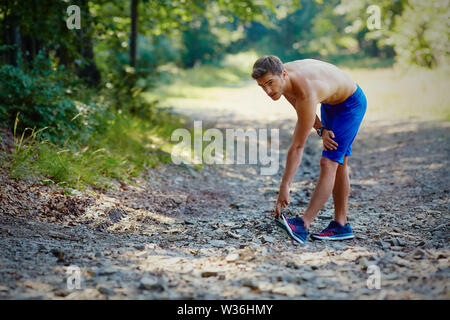 Runner suffers from calf cramp during run exercise in mountains Stock Photo