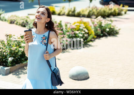 Dark-eyed woman wearing stylish earrings looking at the sky Stock Photo
