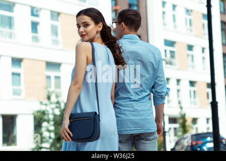 Stylish dark-haired wife walking hand in hand with husband Stock Photo