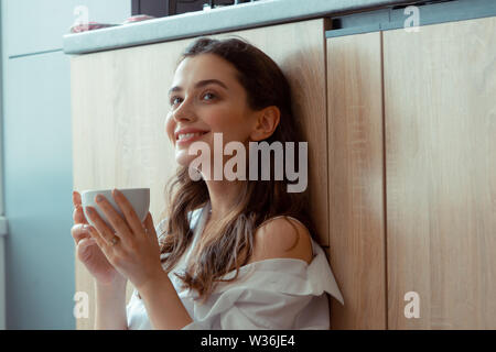 Appealing dark-eyed woman drinking coffee in the morning Stock Photo