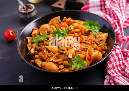 Conchiglie pasta. Italian pasta shells with mushrooms, zucchini and tomato sauce. Stock Photo