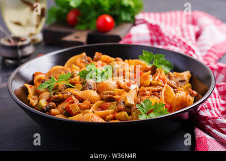Conchiglie pasta. Italian pasta shells with mushrooms, zucchini and tomato sauce. Stock Photo