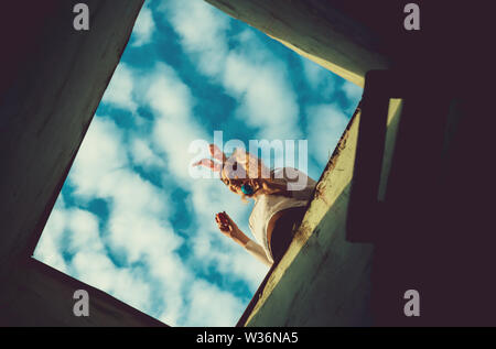 ladder to blue cloudy sky from hole. future life and success. happy easter girl in pink bunny ears with painted eggs, has long blonde hair, smiling ad Stock Photo