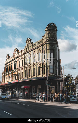 Newtown, New South Wales, Australia - JUNE 23rd, 2018: Pedestrians wait to cross the street in front of the Academy Brand building in Newtown. Stock Photo