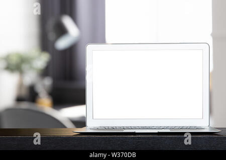 Mock up of blank modern laptop on the black desk. Personal laptop computer on dark wood table in modern white living room. Stock Photo