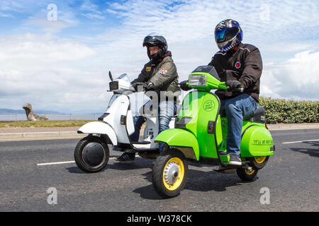 Morecambe, UK. 13th July, 2019. Morecambe Rides Again; The First Kick Scooter Collective and the Vespa Club of Morecambe (COG159) host a rally circuit in the resort which has the honour of being a Vespa Club Of Britain signing on event. Morecambe is back on the scootering map with the first proper scooter rally since the 1980s being held. Scooterists roared into town on their Vespas congregating at Happy Mount Park before a mass rally along the seafront promenade. Credit: Cernan Elias/Alamy Live News Stock Photo