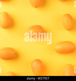 Flat lay pattern of fresh kumquats on a yellow background. Top view Stock Photo